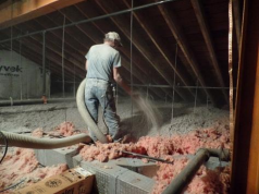 A technician applying blown insulation