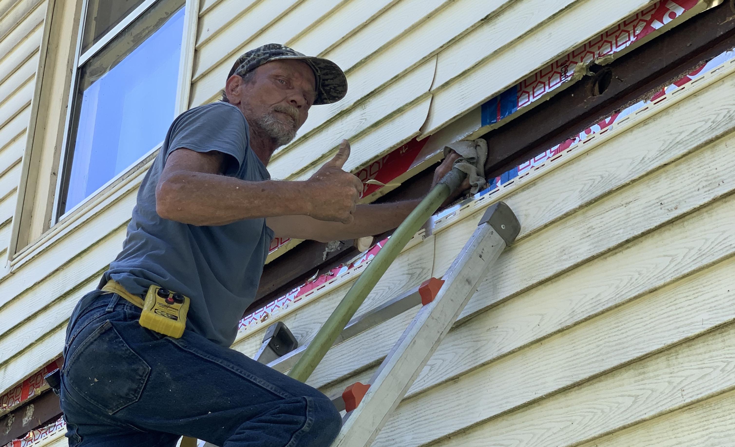 Accurate-Airtight Exteriors Crew Member Giving A Thumbs-Up While Applying Blown-In Cellulose Insulation Accurate-Airtight Exteriors Crew Member Giving A Thumbs-Up While Applying Blown-In Cellulose Insulation