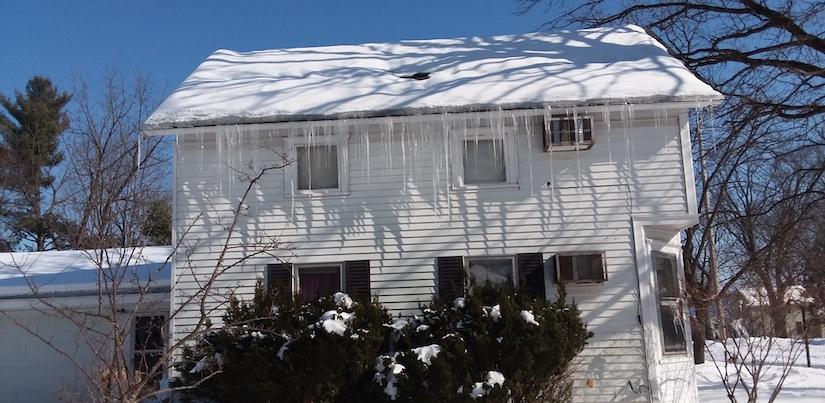 Ice Dam On House House with icicles forming off the edge of the roof (ice dam)