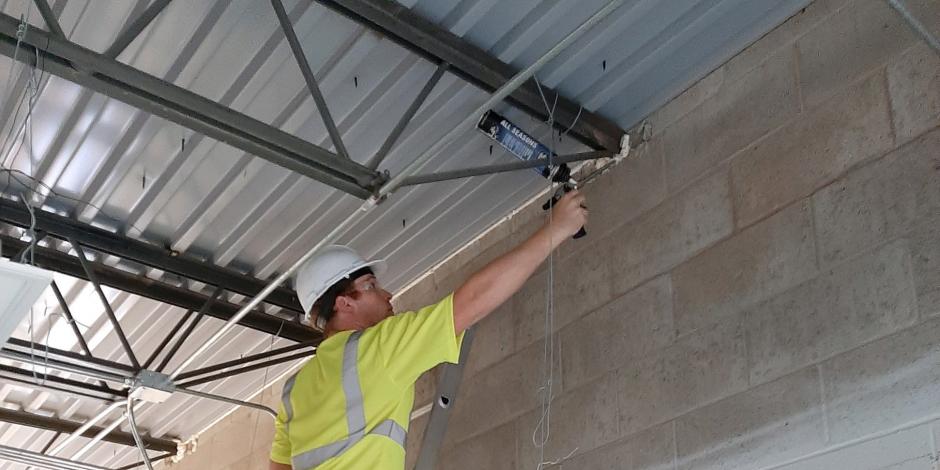Worker applying caulk to commercial ceiling Worker applying caulk to commercial ceiling