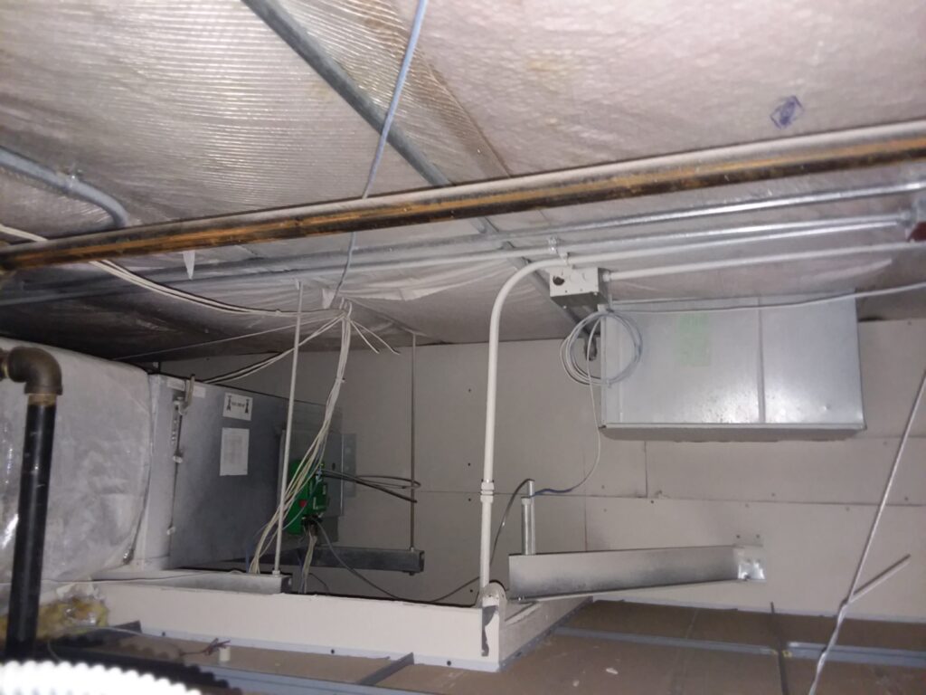 Example of air leaks around electrical penetrations concealed above ceiling tile in a commercial building.