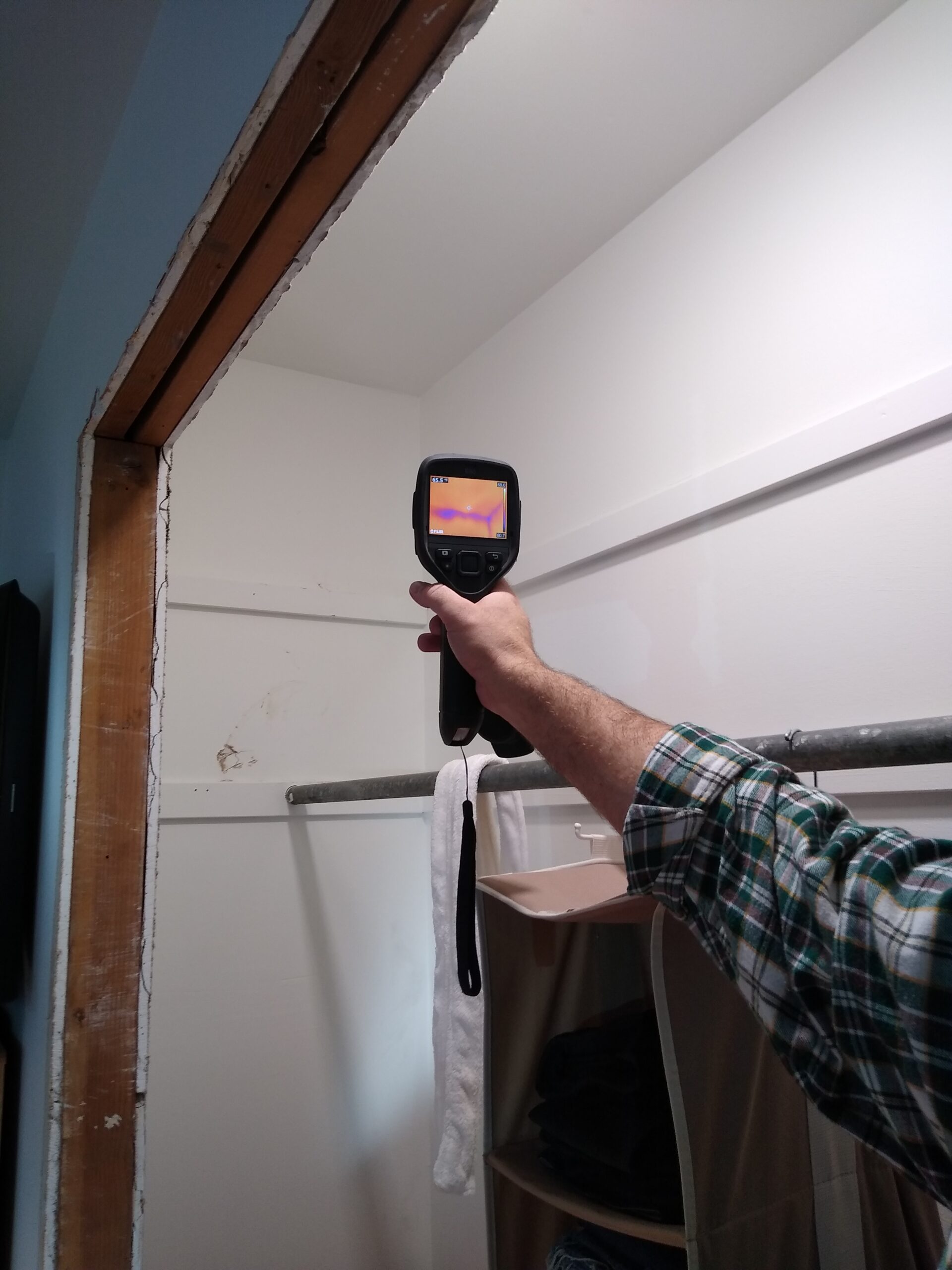 Hand holding infrared camera and looking at heat in wall