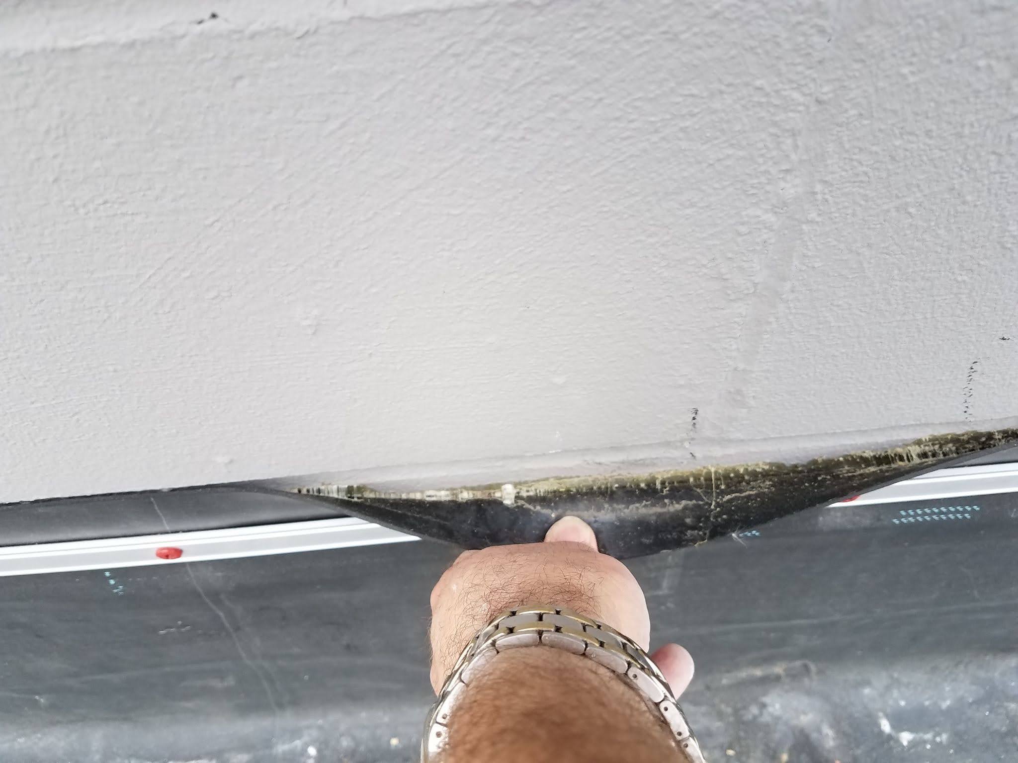 Peeling back the weatherstripping on wall to see the air sealing underneath